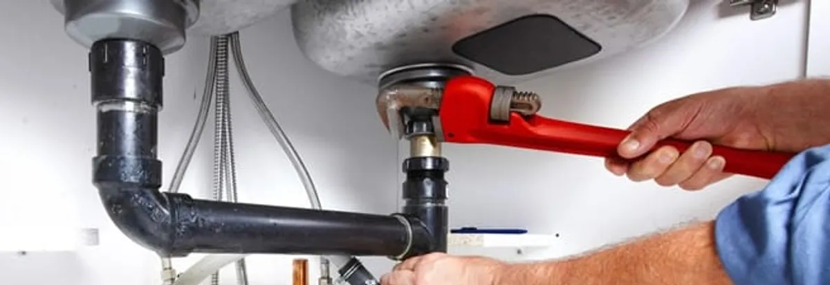 Garbage disposal repair technician tightening the sink drain and disposal connection in Fresno, CA