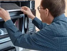 Appliance repair technician replacing a microwave vent filter in Fresno, CA