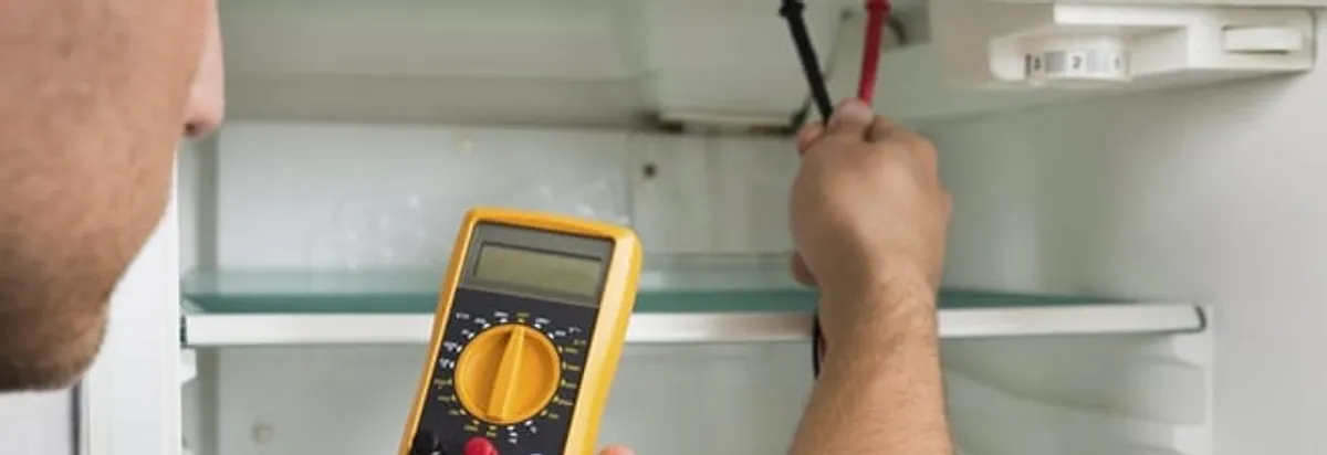 Refrigerator repair technician testing electrical components with a multimeter in Fresno, CA